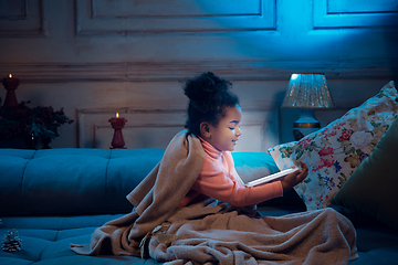 Image showing Happy african-american little girl during video call with laptop and home devices, looks delighted and happy