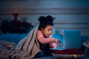 Image showing Happy african-american little girl during video call with laptop and home devices, looks delighted and happy