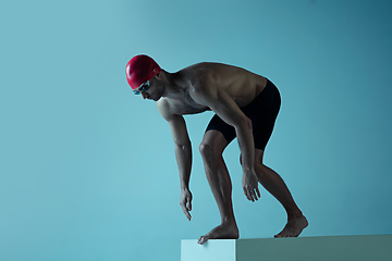 Image showing Professional male swimmer with hat and goggles in motion and action, healthy lifestyle and movement concept. Neoned style.