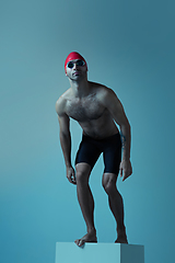 Image showing Professional male swimmer with hat and goggles in motion and action, healthy lifestyle and movement concept. Neoned style.