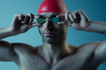 Image showing Professional male swimmer with hat and goggles in motion and action, healthy lifestyle and movement concept. Neoned style.