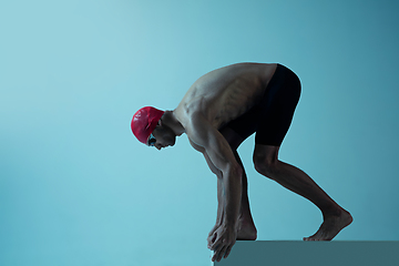 Image showing Professional male swimmer with hat and goggles in motion and action, healthy lifestyle and movement concept. Neoned style.