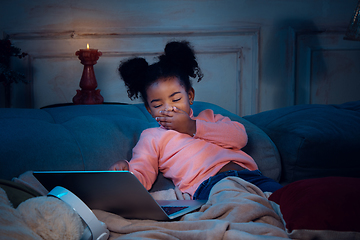 Image showing Happy african-american little girl during video call with laptop and home devices, looks delighted and happy