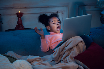 Image showing Happy african-american little girl during video call with laptop and home devices, looks delighted and happy