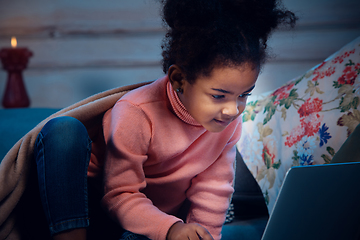 Image showing Happy african-american little girl during video call with laptop and home devices, looks delighted and happy