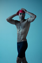 Image showing Professional male swimmer with hat and goggles in motion and action, healthy lifestyle and movement concept. Neoned style.