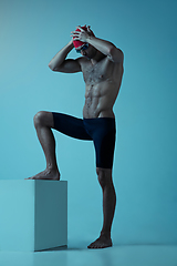 Image showing Professional male swimmer with hat and goggles in motion and action, healthy lifestyle and movement concept. Neoned style.