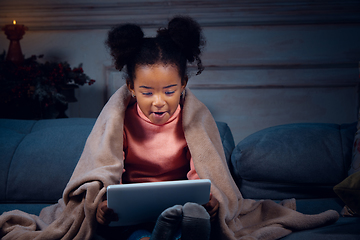 Image showing Happy african-american little girl during video call with laptop and home devices, looks delighted and happy