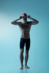 Image showing Professional male swimmer with hat and goggles in motion and action, healthy lifestyle and movement concept. Neoned style.