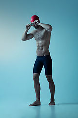 Image showing Professional male swimmer with hat and goggles in motion and action, healthy lifestyle and movement concept. Neoned style.