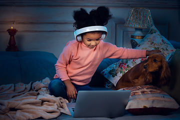 Image showing Happy african-american little girl during video call with laptop and home devices, looks delighted and happy