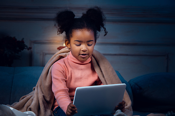 Image showing Happy african-american little girl during video call with laptop and home devices, looks delighted and happy