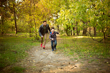 Image showing Father and son walking and having fun in autumn forest, look happy and sincere