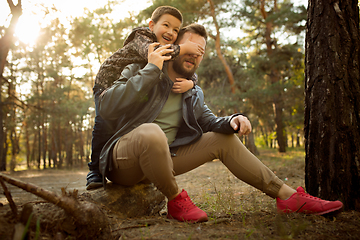 Image showing Father and son walking and having fun in autumn forest, look happy and sincere