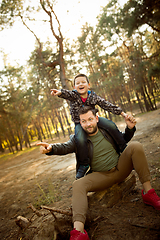 Image showing Father and son walking and having fun in autumn forest, look happy and sincere