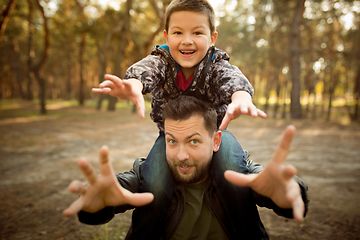 Image showing Father and son walking and having fun in autumn forest, look happy and sincere