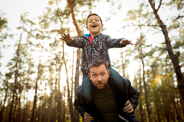 Image showing Father and son walking and having fun in autumn forest, look happy and sincere