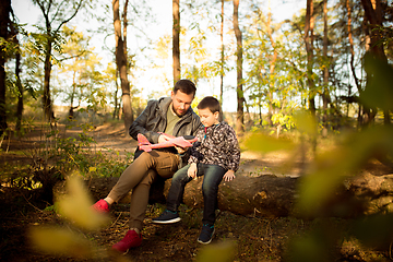 Image showing Father and son walking and having fun in autumn forest, look happy and sincere