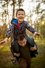 Image showing Father and son walking and having fun in autumn forest, look happy and sincere