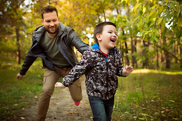 Image showing Father and son walking and having fun in autumn forest, look happy and sincere