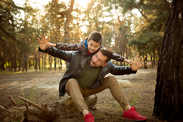 Image showing Father and son walking and having fun in autumn forest, look happy and sincere