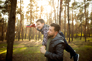 Image showing Father and son walking and having fun in autumn forest, look happy and sincere