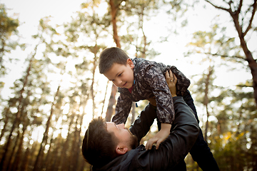 Image showing Father and son walking and having fun in autumn forest, look happy and sincere