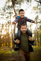 Image showing Father and son walking and having fun in autumn forest, look happy and sincere