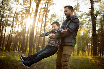 Image showing Father and son walking and having fun in autumn forest, look happy and sincere