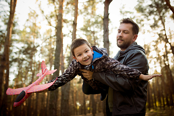 Image showing Father and son walking and having fun in autumn forest, look happy and sincere