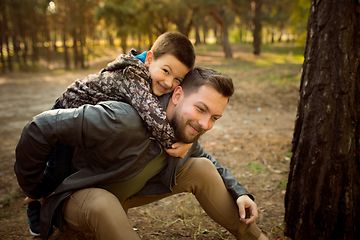 Image showing Father and son walking and having fun in autumn forest, look happy and sincere