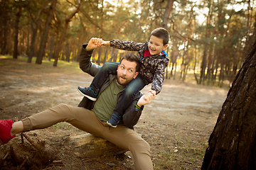 Image showing Father and son walking and having fun in autumn forest, look happy and sincere