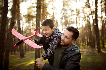 Image showing Father and son walking and having fun in autumn forest, look happy and sincere