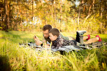 Image showing Father and son walking and having fun in autumn forest, look happy and sincere
