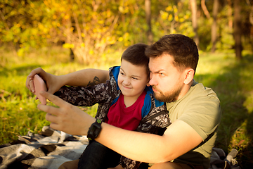 Image showing Father and son walking and having fun in autumn forest, look happy and sincere