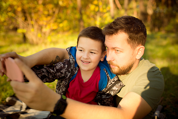 Image showing Father and son walking and having fun in autumn forest, look happy and sincere