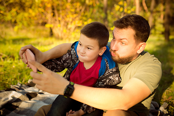 Image showing Father and son walking and having fun in autumn forest, look happy and sincere