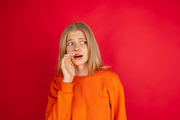 Image showing Portrait of young caucasian woman with bright emotions isolated on red studio background