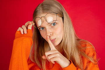 Image showing Portrait of young caucasian woman with bright emotions isolated on red studio background