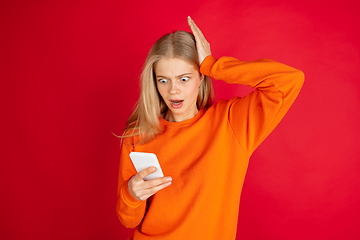 Image showing Portrait of young caucasian woman with bright emotions isolated on red studio background