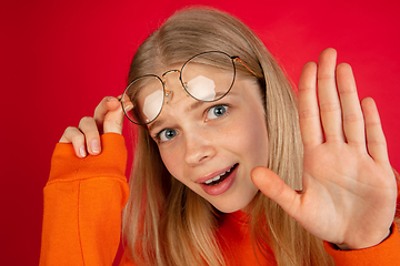 Image showing Portrait of young caucasian woman with bright emotions isolated on red studio background