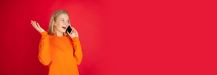 Image showing Portrait of young caucasian woman with bright emotions isolated on red studio background