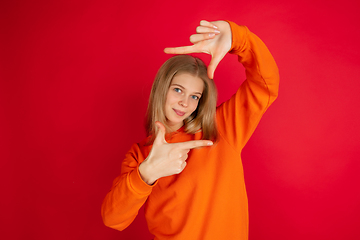 Image showing Portrait of young caucasian woman with bright emotions isolated on red studio background