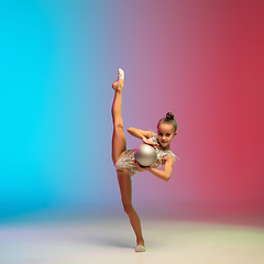 Image showing Little caucasian girl, rhytmic gymnast training, performing isolated on gradient blue-red studio background in neon