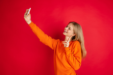 Image showing Portrait of young caucasian woman with bright emotions isolated on red studio background