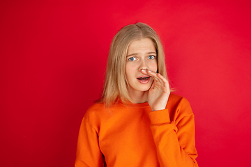 Image showing Portrait of young caucasian woman with bright emotions isolated on red studio background