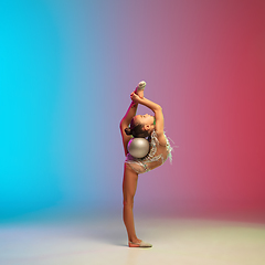 Image showing Little caucasian girl, rhytmic gymnast training, performing isolated on gradient blue-red studio background in neon