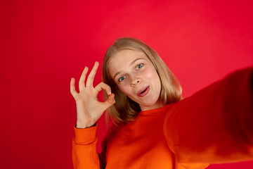 Image showing Portrait of young caucasian woman with bright emotions isolated on red studio background