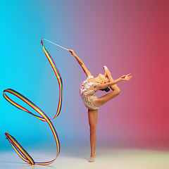 Image showing Little caucasian girl, rhytmic gymnast training, performing isolated on gradient blue-red studio background in neon