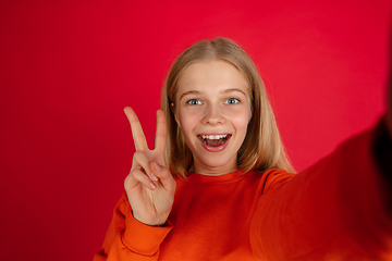 Image showing Portrait of young caucasian woman with bright emotions isolated on red studio background